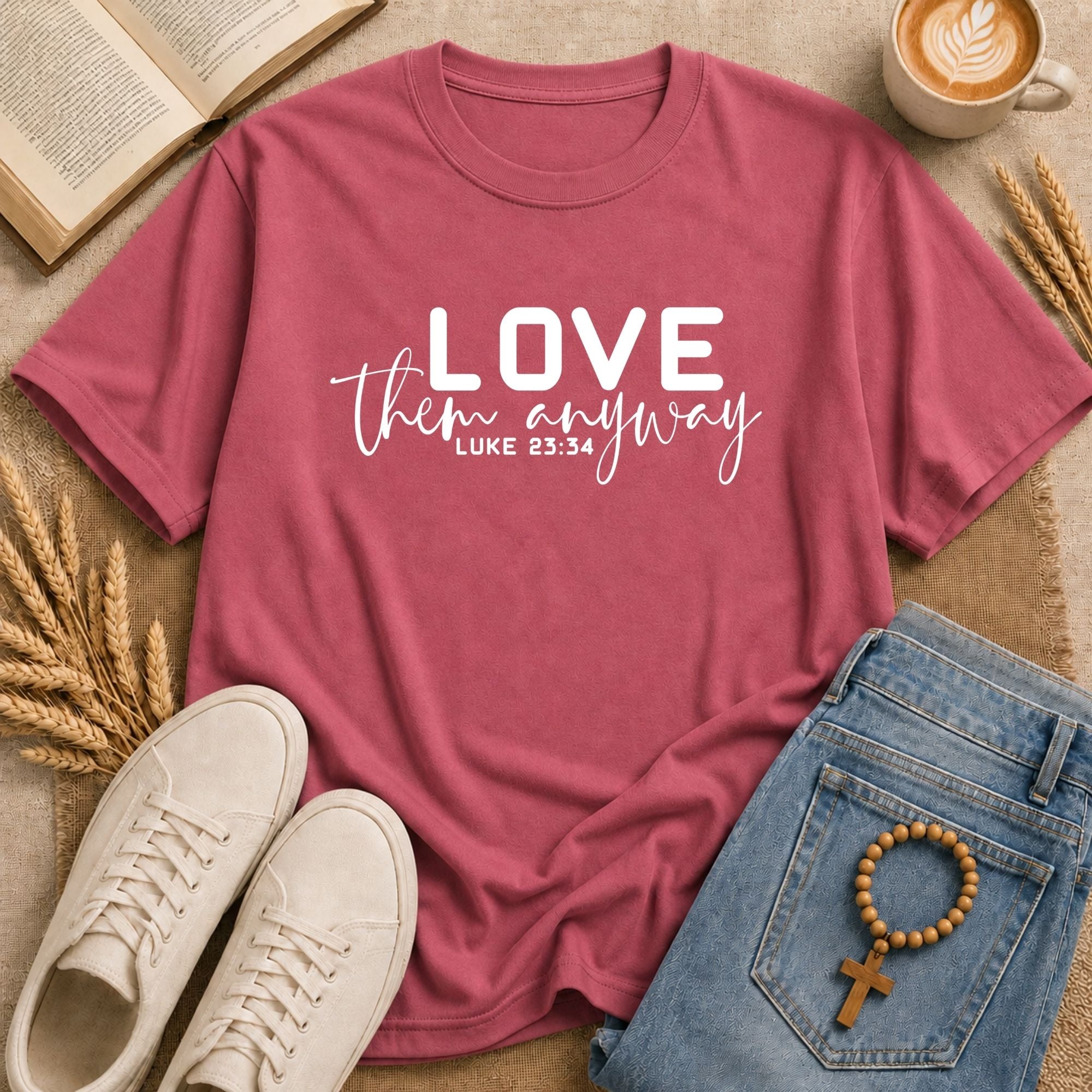 unisex t-shirt with white mixed-font print reading Love Them Anyway and Bible verse Luke 23:34